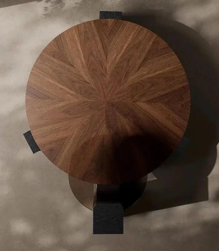 Wooden stool with a circular top and black legs on a textured surface