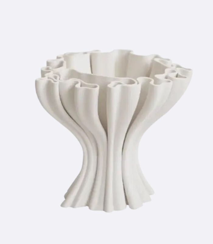 A white ceramic vase with an abstract, undulating shape, inspired by coral and seashells.