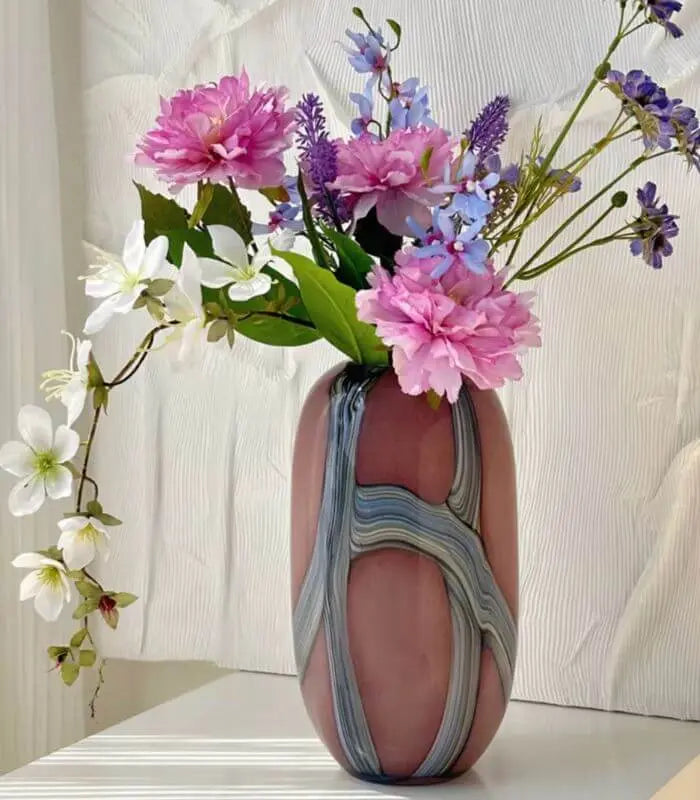 Pink and gray marbled vase with flowers on a white surface